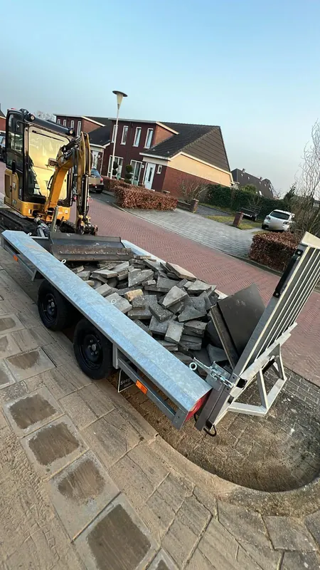Minigraver en aanhanger met opgebroken tegels